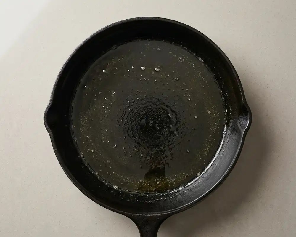 Heiße Gusseisenpfanne mit geschmolzener Butter für Dutch Baby von oben fotografiert
